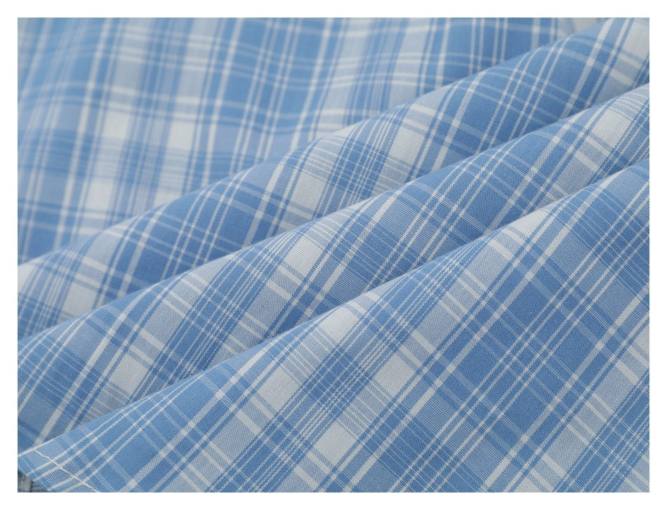 Close-up of blue and white plaid fabric arranged in soft diagonal folds.