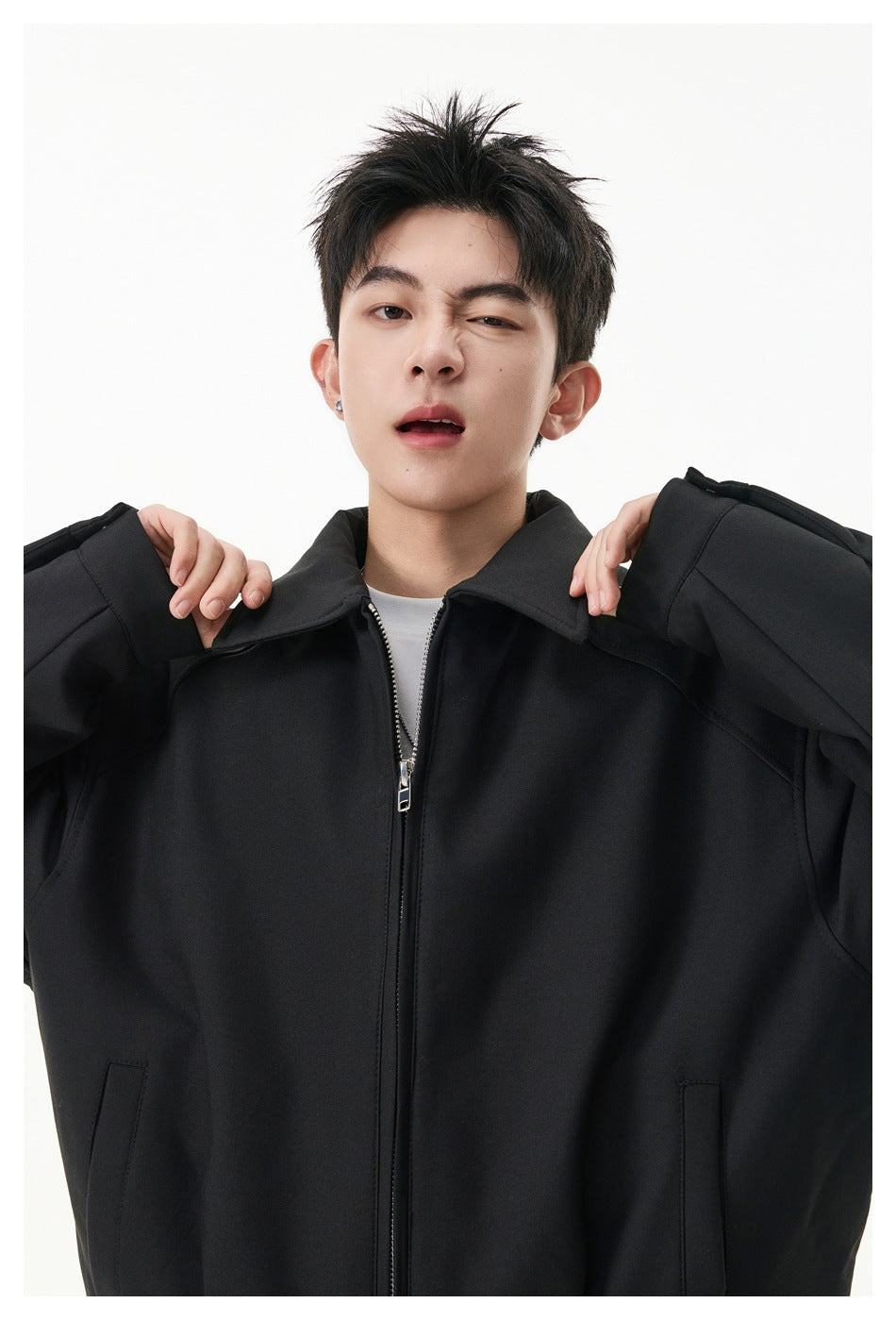 Close view of a model wearing a black zip-front jacket with a pointed collar and roomy sleeves.