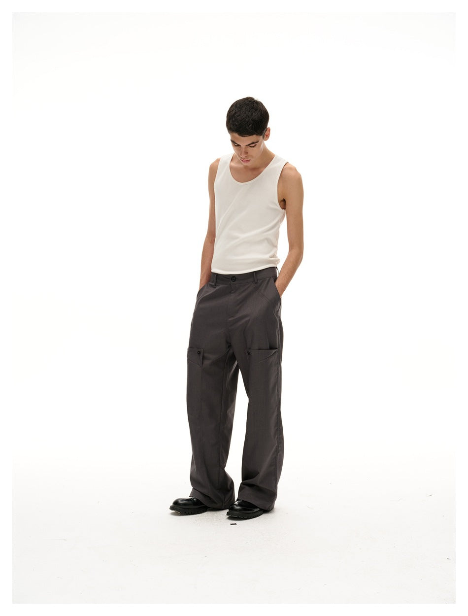 Model looking down in a cream tank top and charcoal wide-leg trousers with large front cargo pockets.