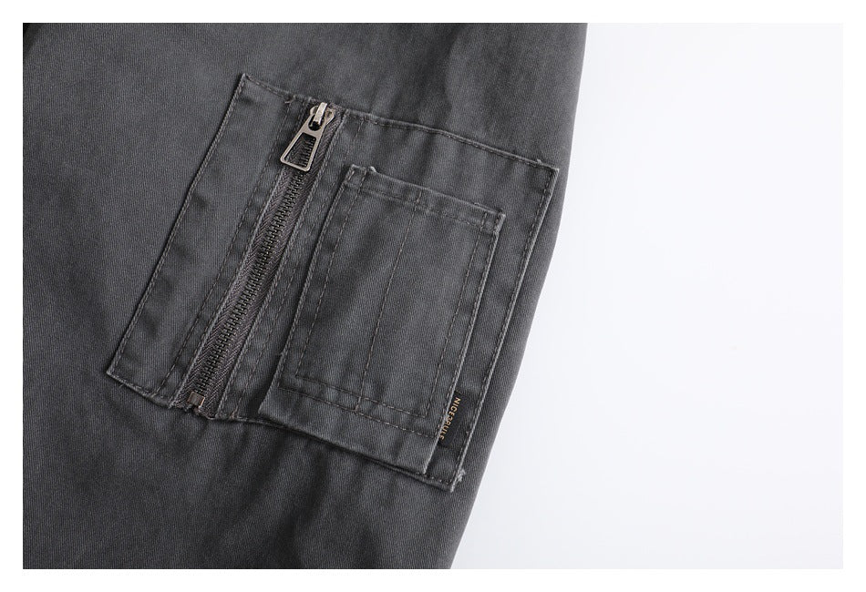 Close-up of a charcoal jacket sleeve pocket with a vertical zipper and a stitched patch pocket.