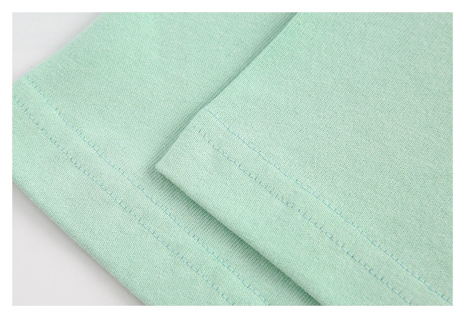 Close-up of pale mint fabric with a folded hem and visible stitching.