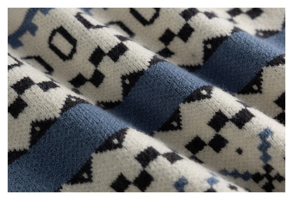 Close-up of an ivory knit sweater with black geometric motifs and broad dusty blue bands.