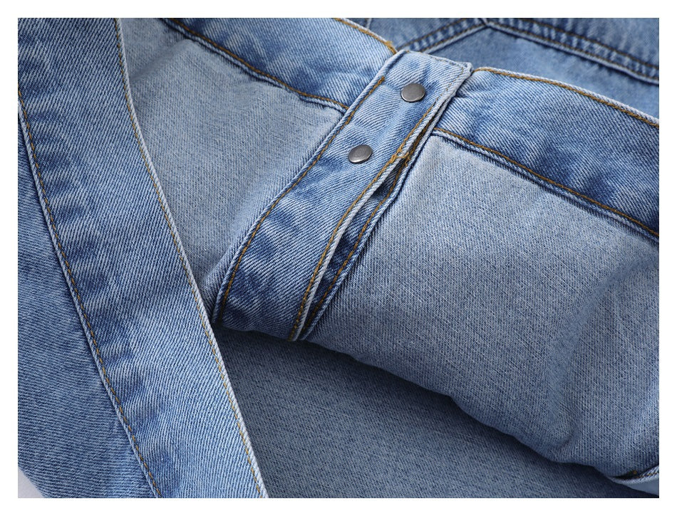 Close-up of light blue denim with two silver snap buttons, folded fabric, and contrasting stitching.