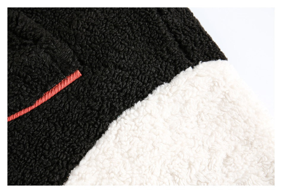 Close-up of black and white curly-pile jacket panels with rust-colored piping.