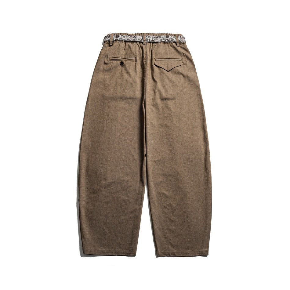 Back view of light brown wide-leg trousers with an elastic waistband, one button welt pocket and one flap pocket