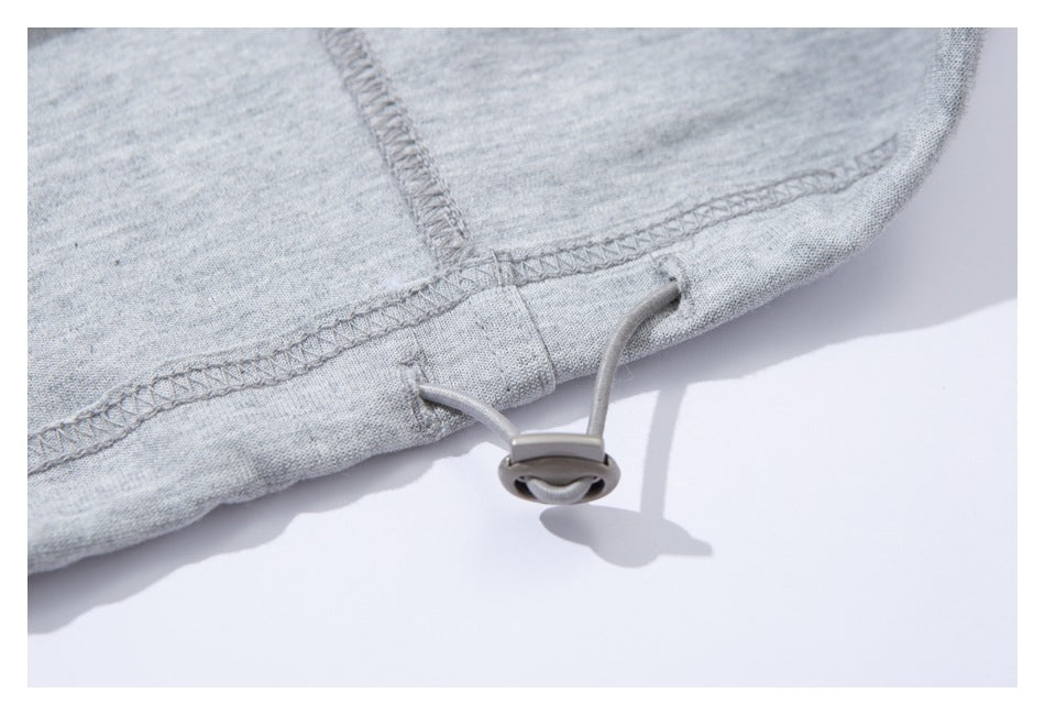 Close-up of a light gray sweatpants hem with an adjustable drawcord and toggle.