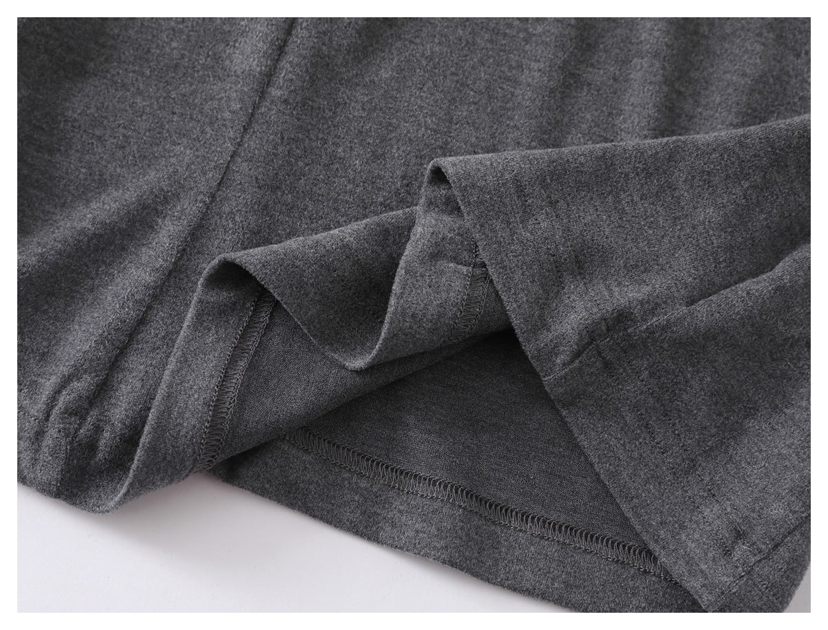Close-up of a charcoal gray garment showing its folded hem and interior overlock stitching.