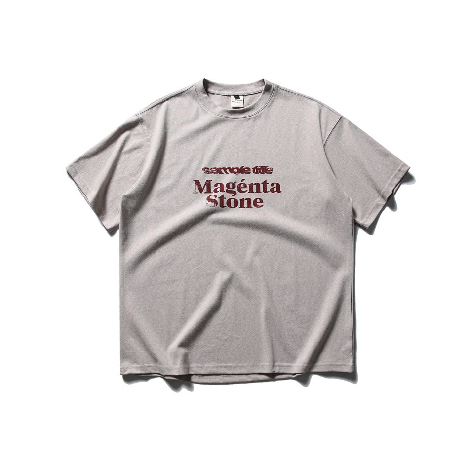 Light gray short-sleeve crew-neck T-shirt with burgundy 'Magénta Stone' text print on the chest, flat lay