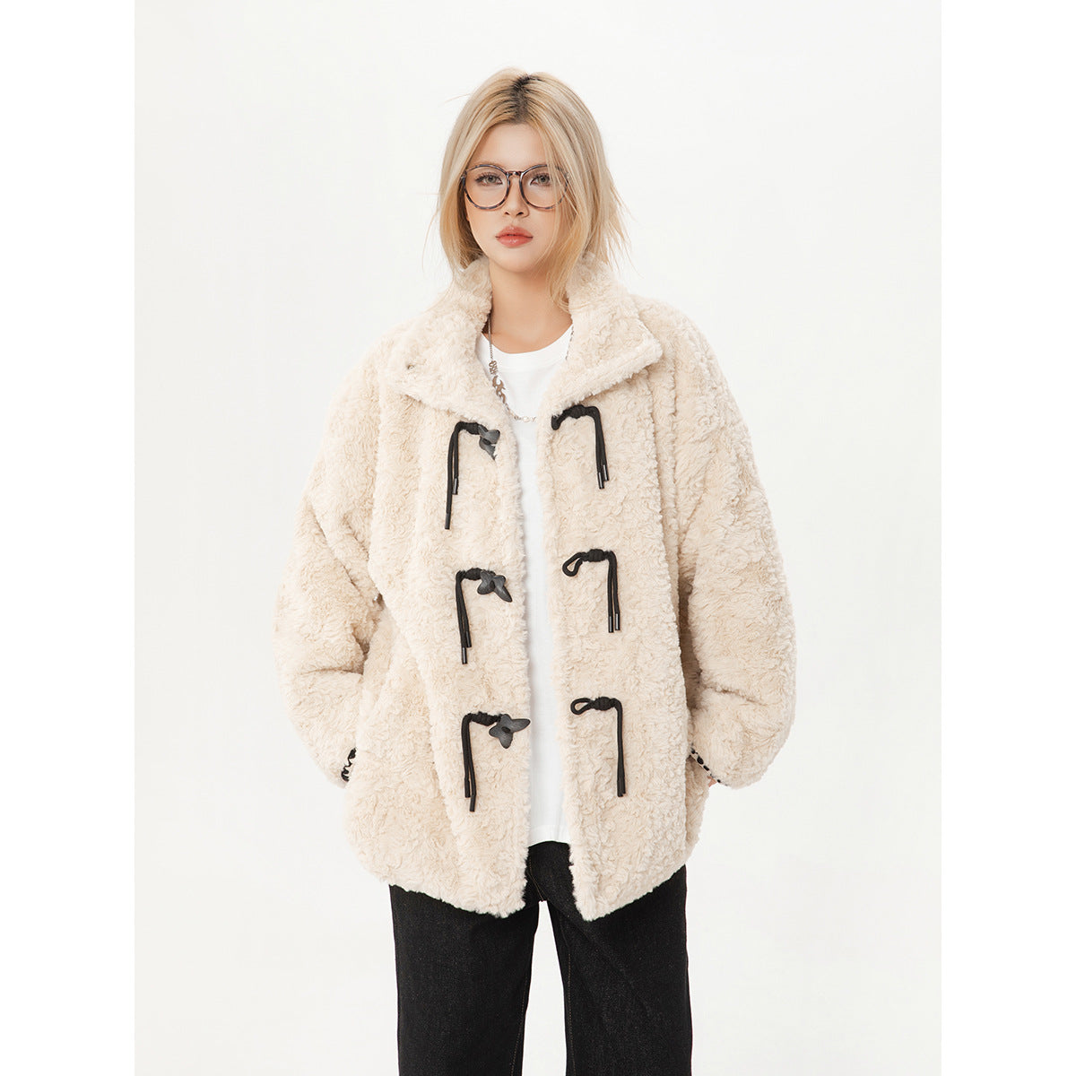 Front view of a model in an ivory textured coat with black toggle closures and a wide collar.