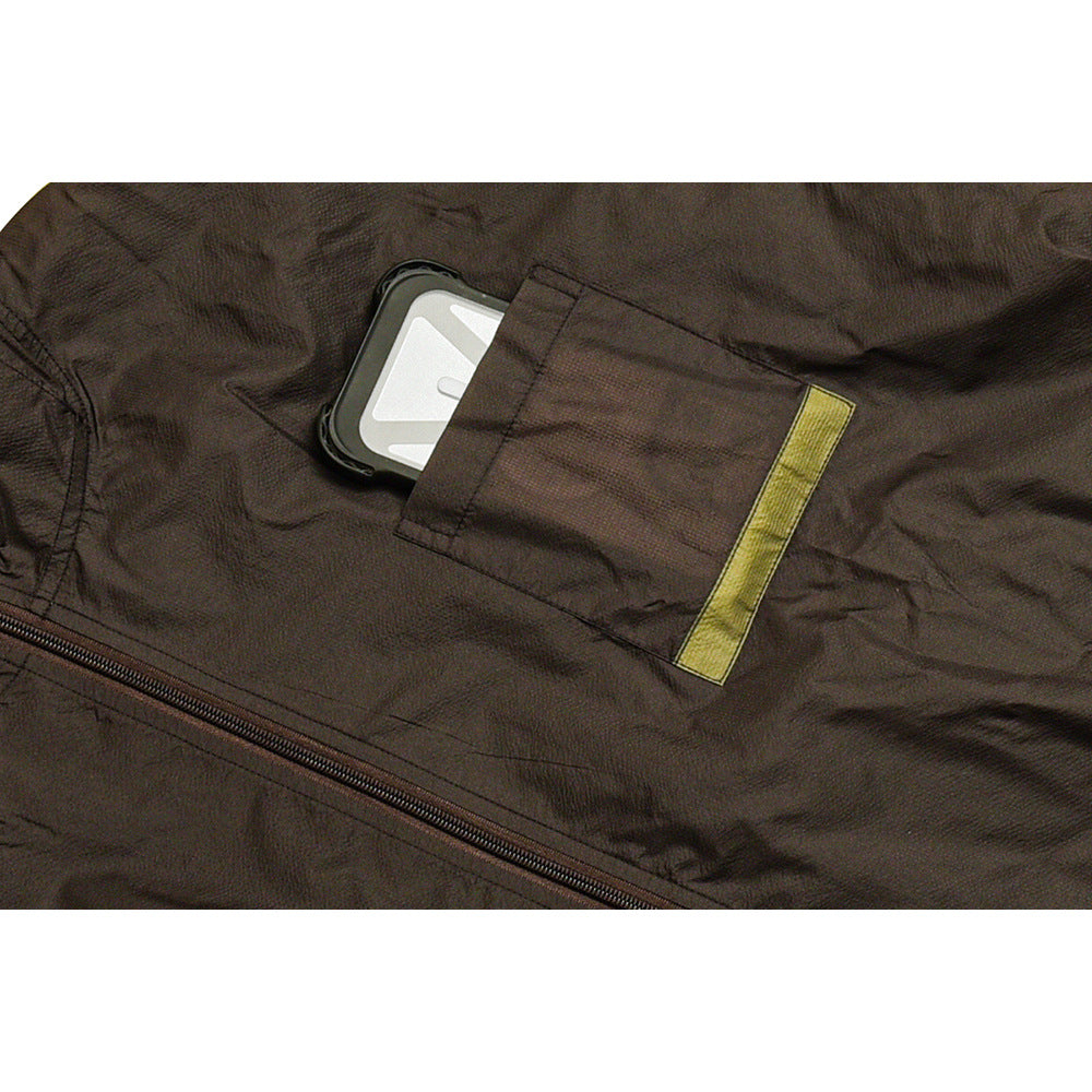 Close-up of a dark jacket pocket with a yellow fabric tab and a small gray item protruding above the zipper.