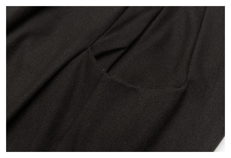 Close-up of a slanted pocket opening on dark charcoal trousers.