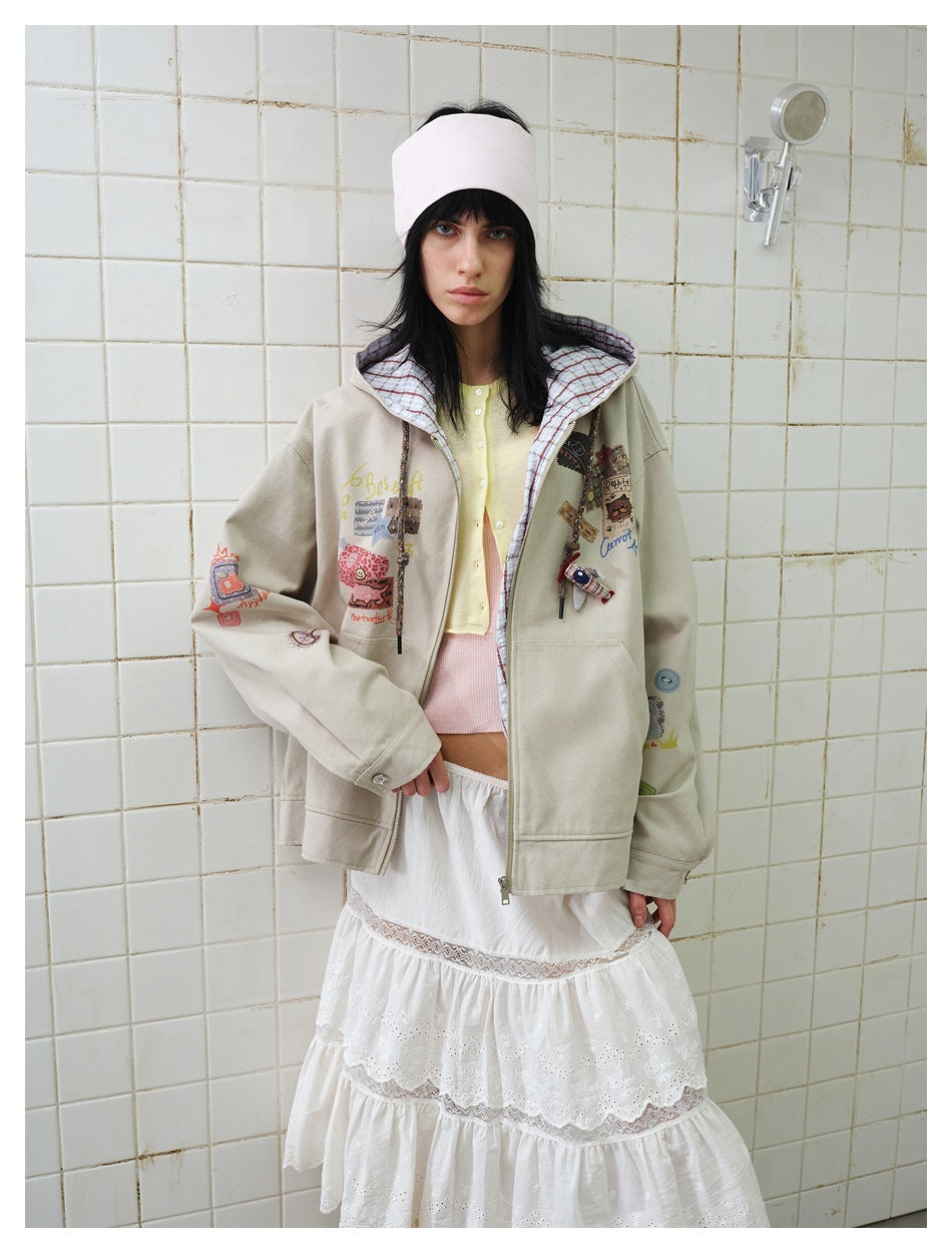 Model wearing open beige hooded jacket over a yellow cardigan and white tiered skirt against a tiled wall