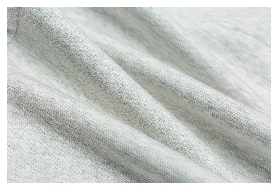 Macro view of the soft-looking light gray marl knit fabric, gathered in folds.