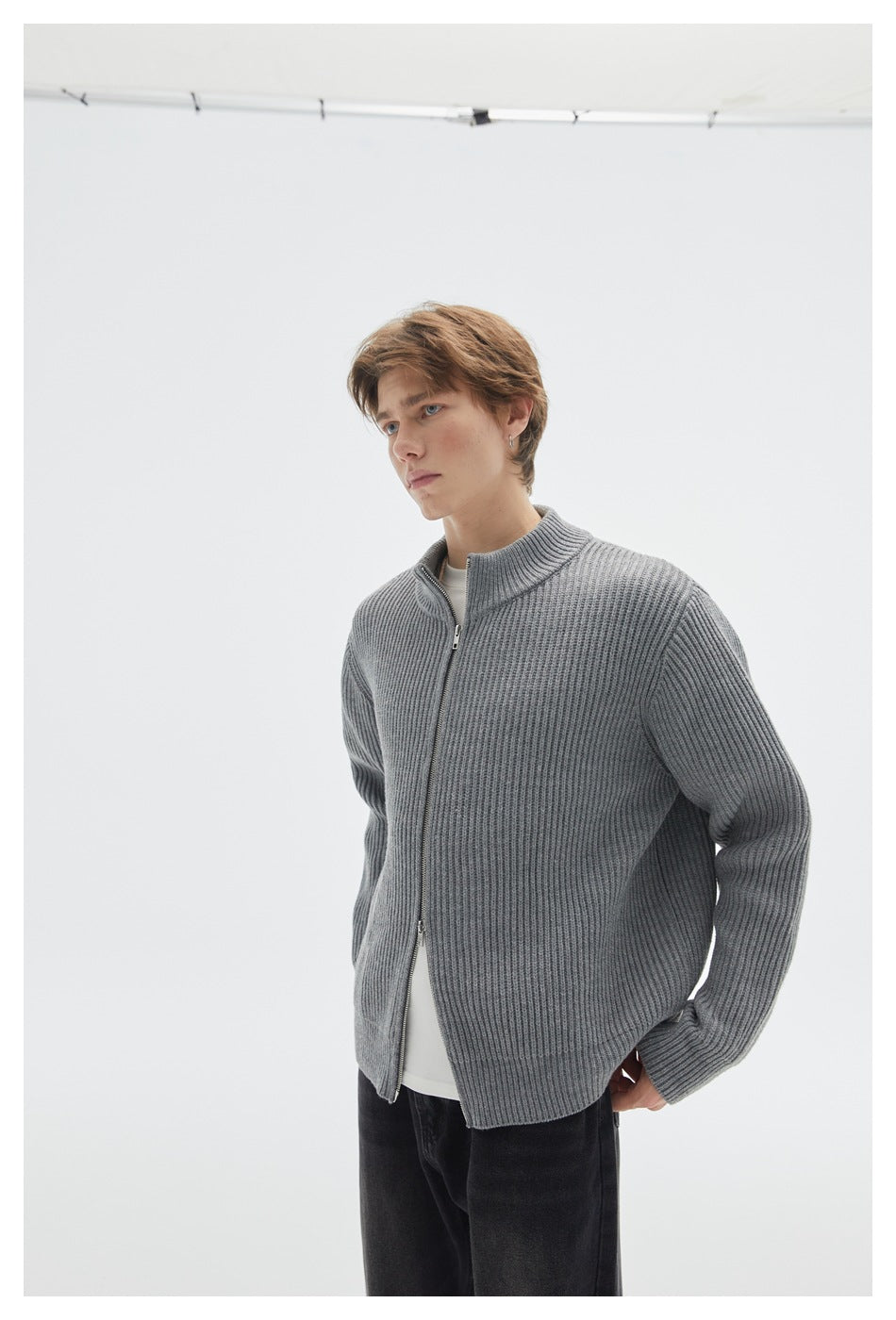 Angled view of a model wearing a gray rib-knit zip cardigan with a stand collar.