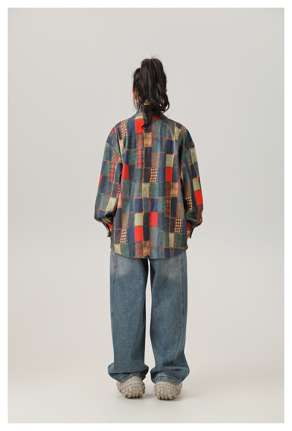 Back view of a model wearing an oversized patchwork block print shirt with wide-leg jeans