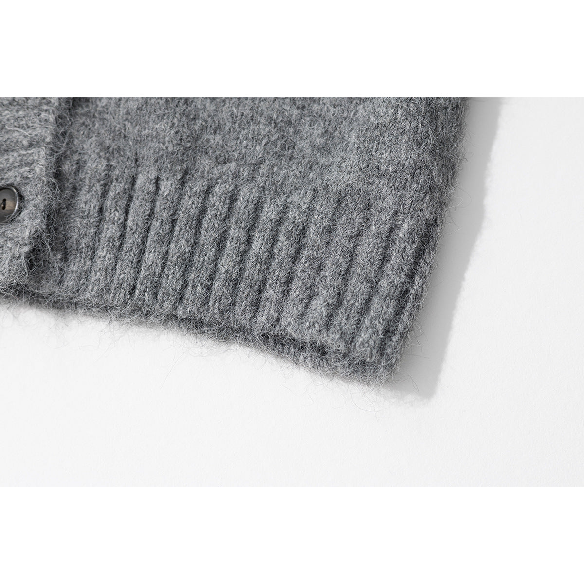 Close-up of the gray cardigan's ribbed cuff and hem, with part of a button visible.