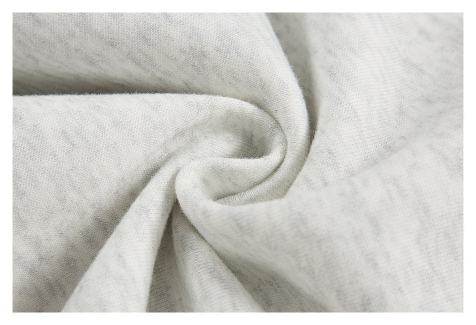 Close-up of pale gray fabric gathered into a soft spiral fold, showing its subtle mottled texture.
