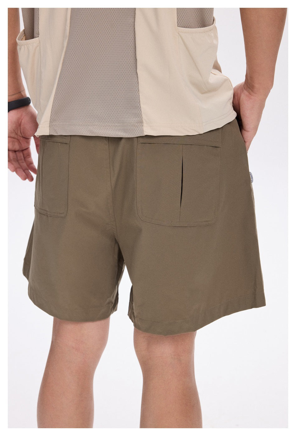 Rear view of a person wearing khaki shorts with two large back pockets and a beige mesh-panel shirt.