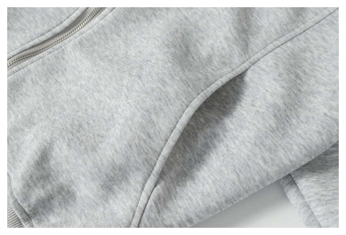 Close-up of a curved seam and piping on light gray heather jacket fabric.
