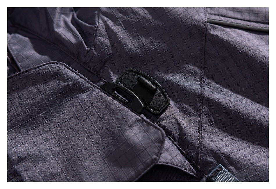 Close-up of a black plastic buckle fastening on charcoal grid-patterned jacket fabric.