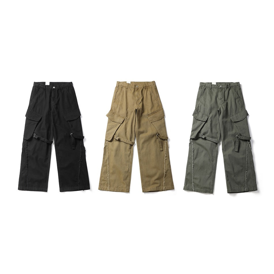 Front views of wide-leg cargo pants in black, tan and gray-green, each with flap pockets and adjustable straps.