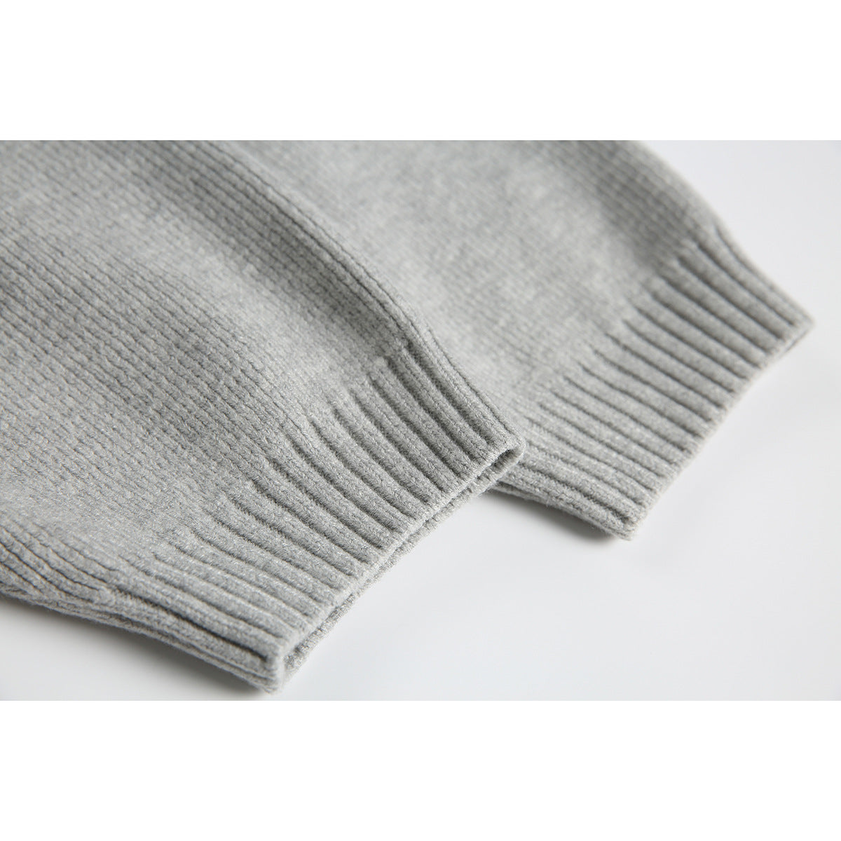 Close-up of the light gray sweater’s ribbed sleeve cuff and knit texture.