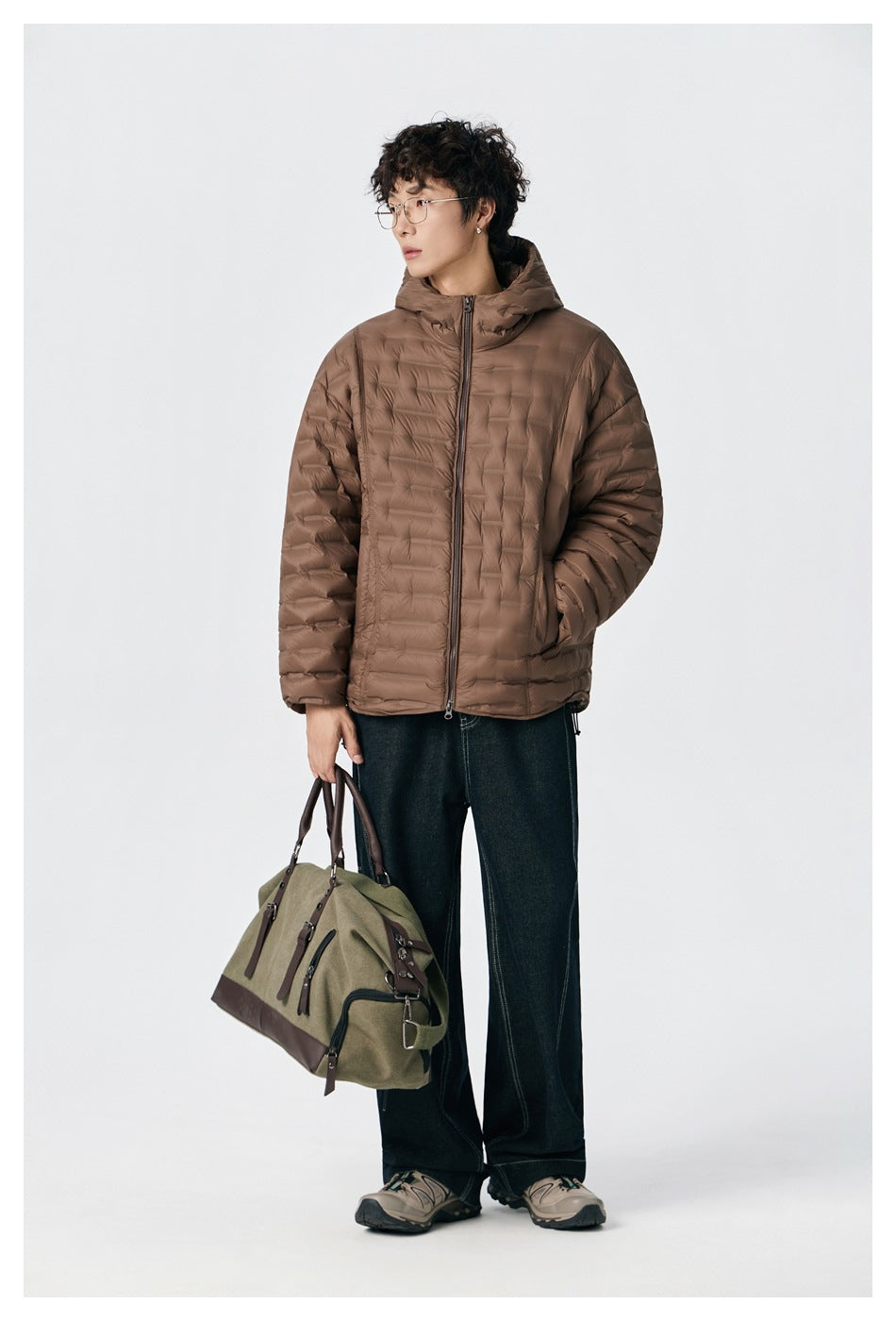 Model wearing a brown quilted hooded jacket zipped at the front with dark jeans.