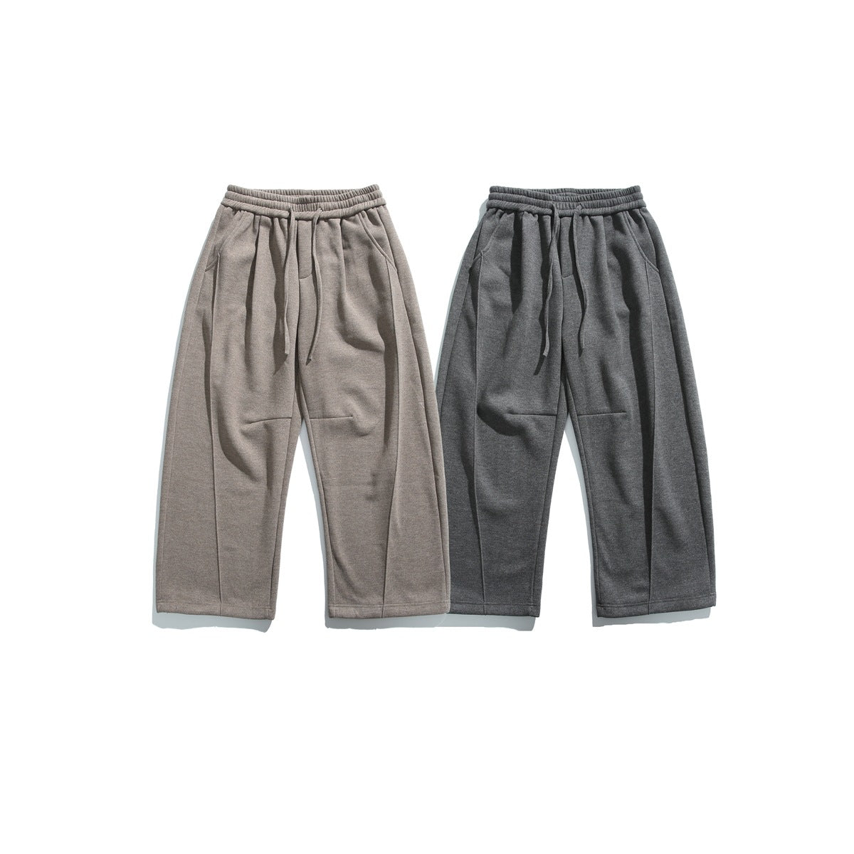 Front views of loose drawstring pants in taupe and charcoal, laid flat side by side.