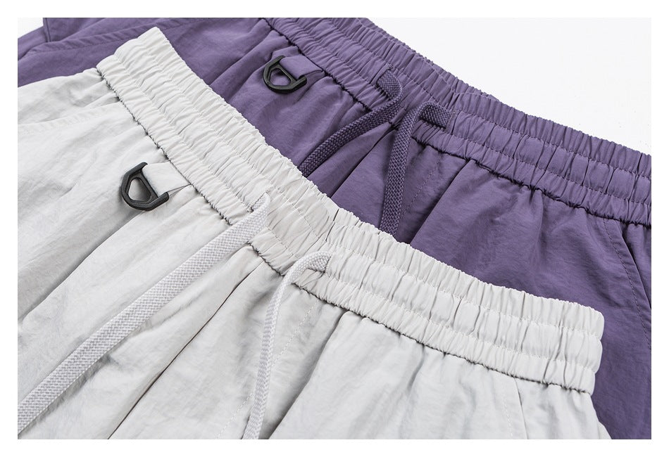 Close-up of white and purple pants showing elastic drawstring waistbands and black D-ring accents.