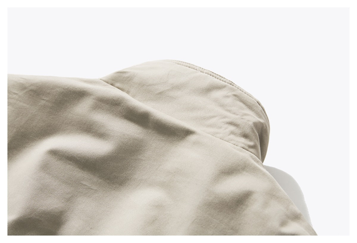 Close-up of a beige jacket shoulder seam and curved panel.
