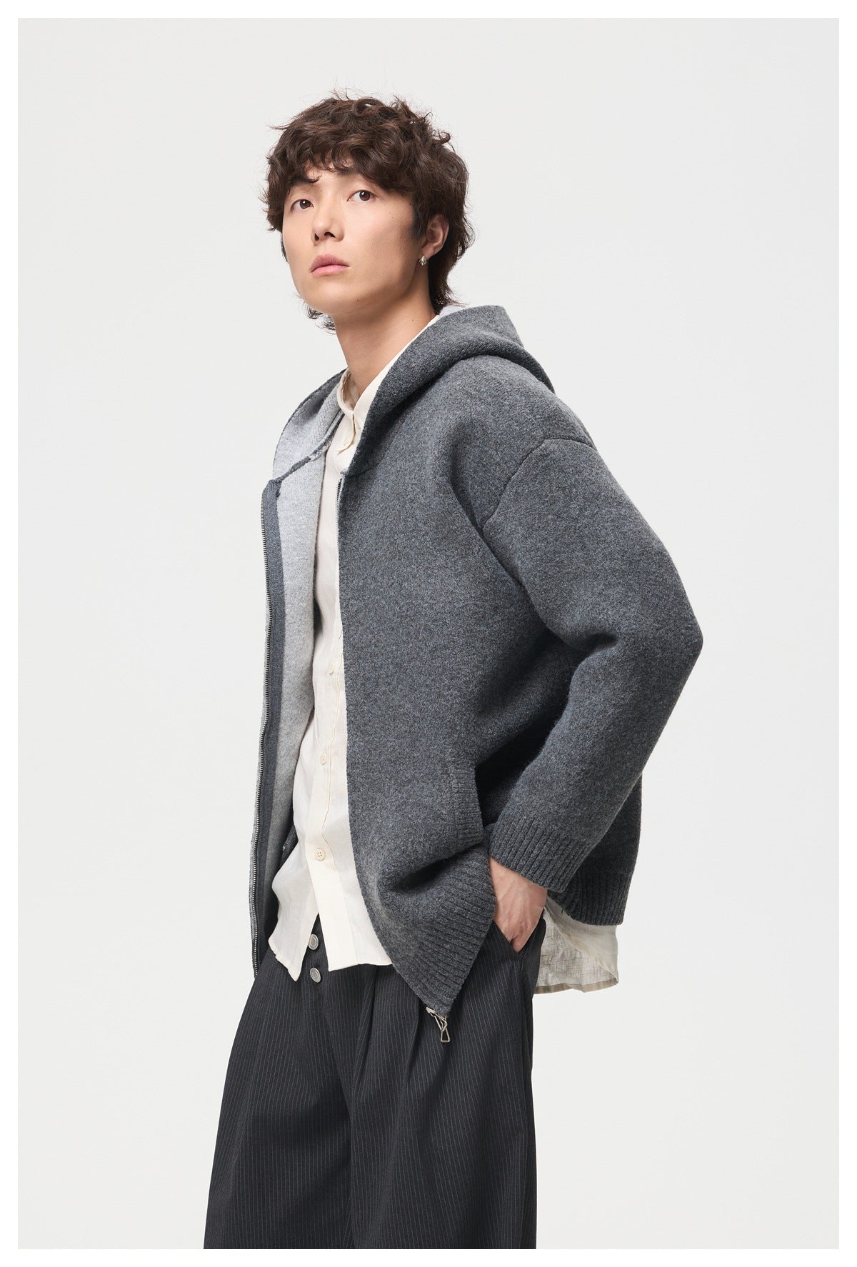 Model wearing an open charcoal gray hooded zip jacket over a white shirt.