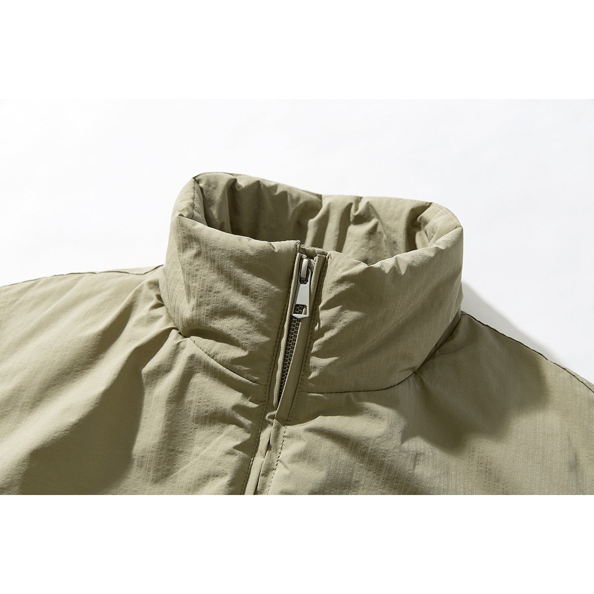 Close-up of an olive-beige jacket’s tall stand collar and central zipper.