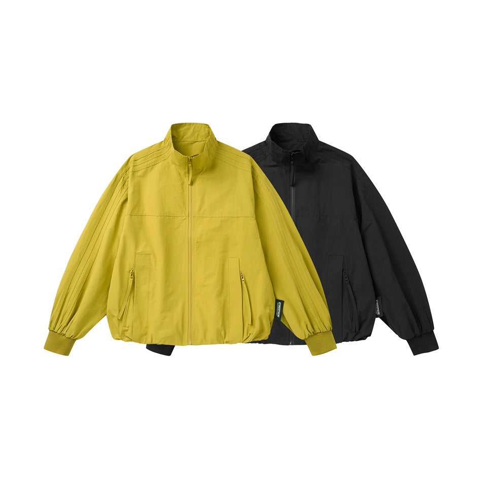 Front view of mustard yellow and black zip-up jackets with stand collars, pockets, and ribbed cuffs.