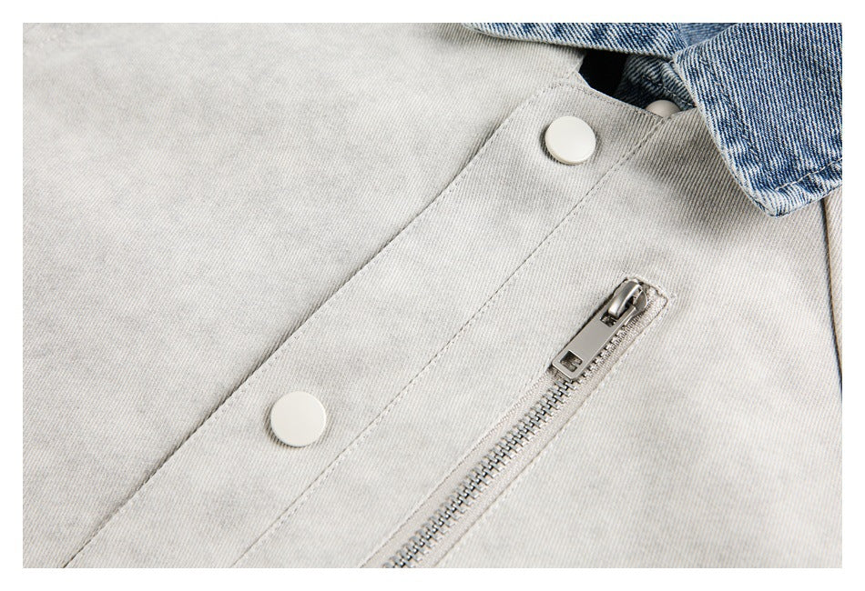Close-up of a light gray jacket with white snap buttons and a metal zipper beside blue denim trim.