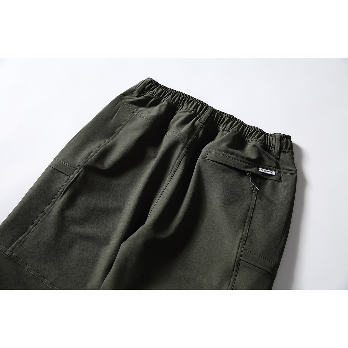 Back view of dark olive pants with an elastic waist, belt loops, stitched panels, and a zip pocket.
