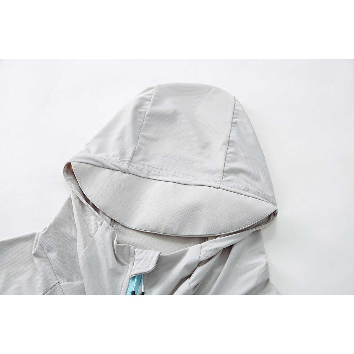 Close-up of a light gray jacket hood with a broad brim and turquoise zipper cord.