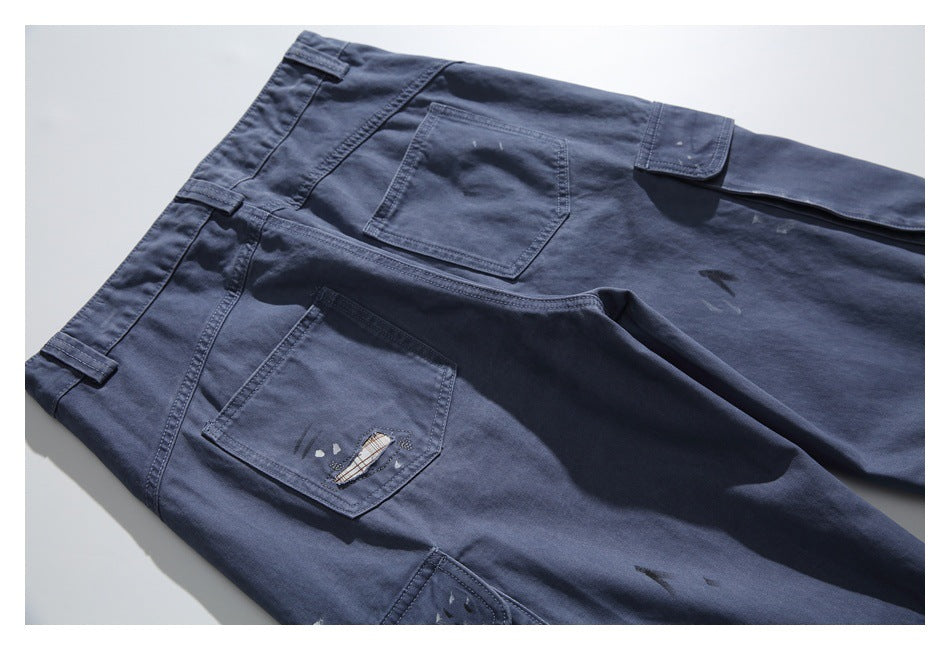Close-up of dark navy trousers with several pockets and small distressed marks.