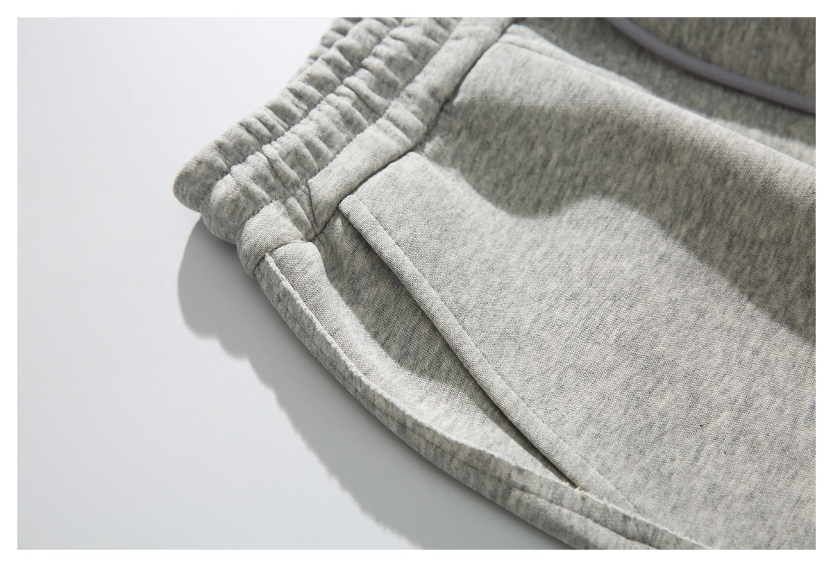 Close-up of a light gray heather sweatpants pocket opening and elastic waistband.