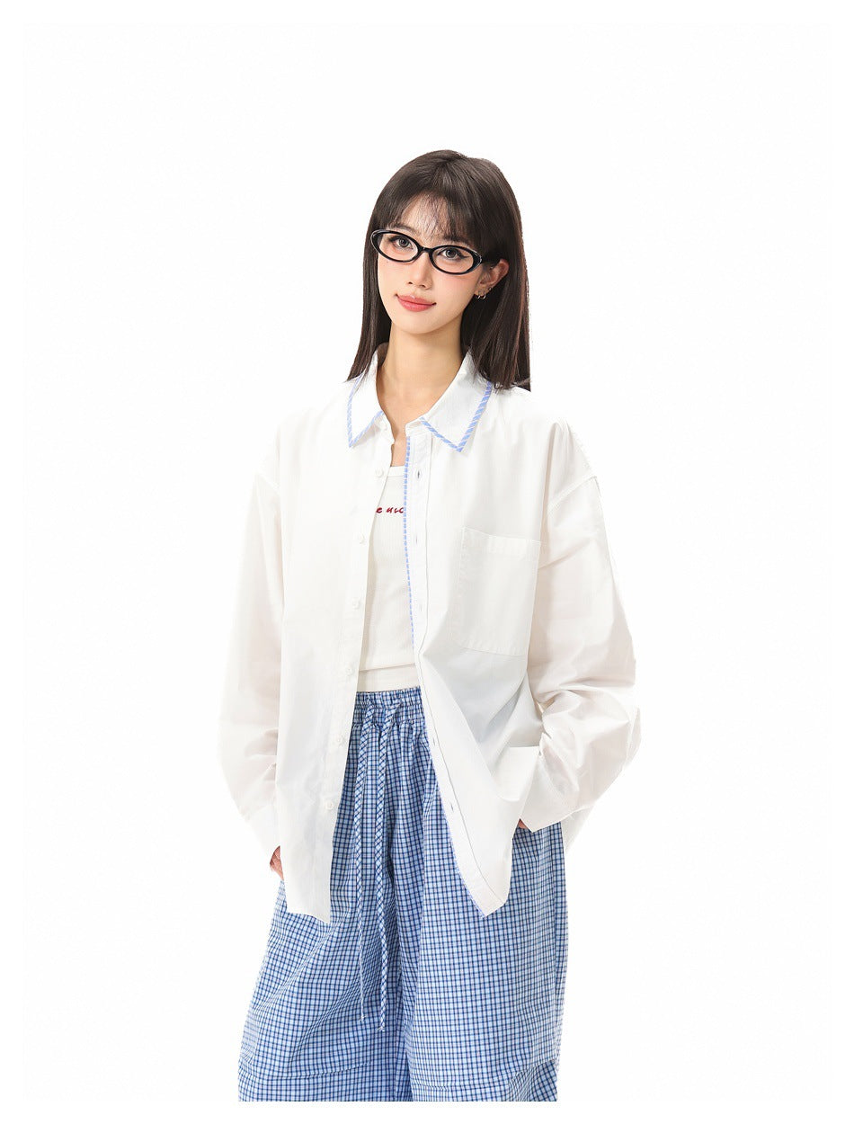 Model wearing an open white button-up shirt with blue collar trim and loose blue checked trousers.
