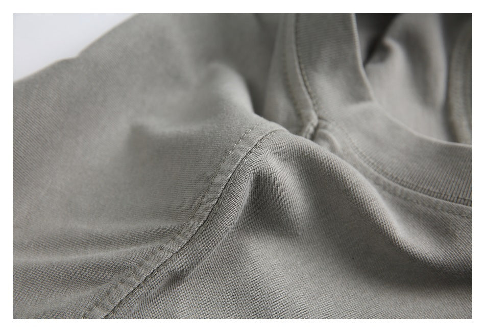 Close-up of a gray T-shirt shoulder seam and ribbed crew neckline stitching.