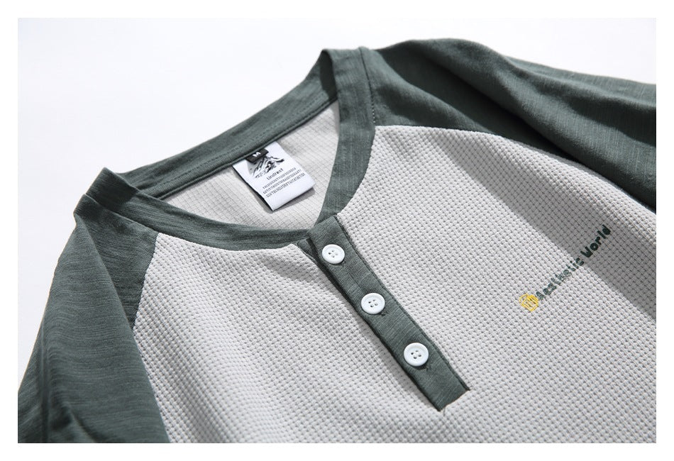 Close-up of the gray textured shirt's dark green collar, three-button placket, sleeve, chest embroidery, and neck label.