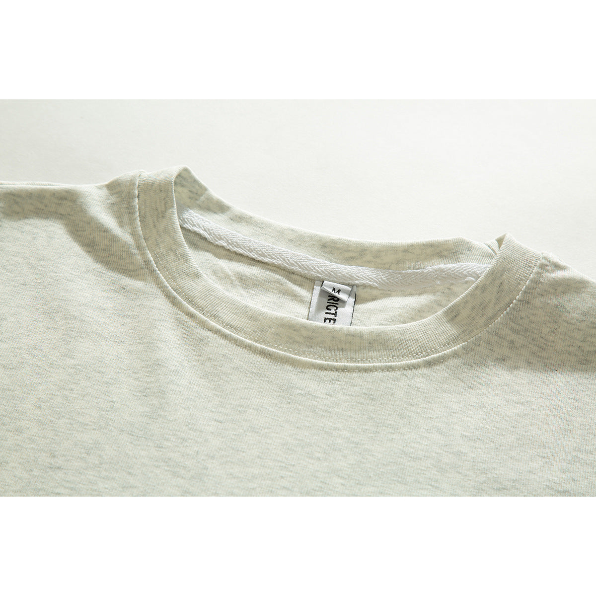 Close-up of a pale gray mottled T-shirt neckline and ribbed crew neck with a visible inner label.