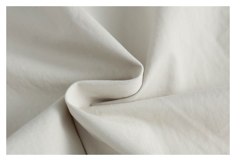 Close-up of softly draped off-white fabric showing its fine surface texture.