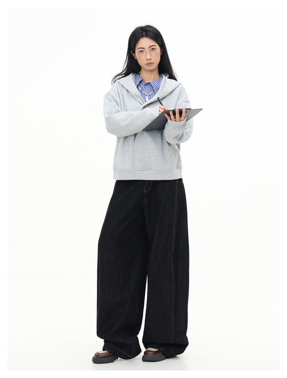 Model in gray hooded sweatshirt over striped shirt and wide-leg dark jeans, writing on a tablet