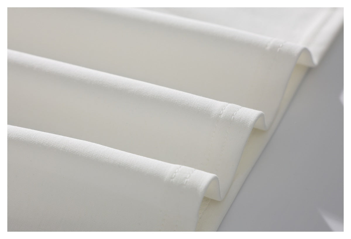 Close-up of plain white fabric folded in parallel layers, showing its smooth woven surface and stitched edges.