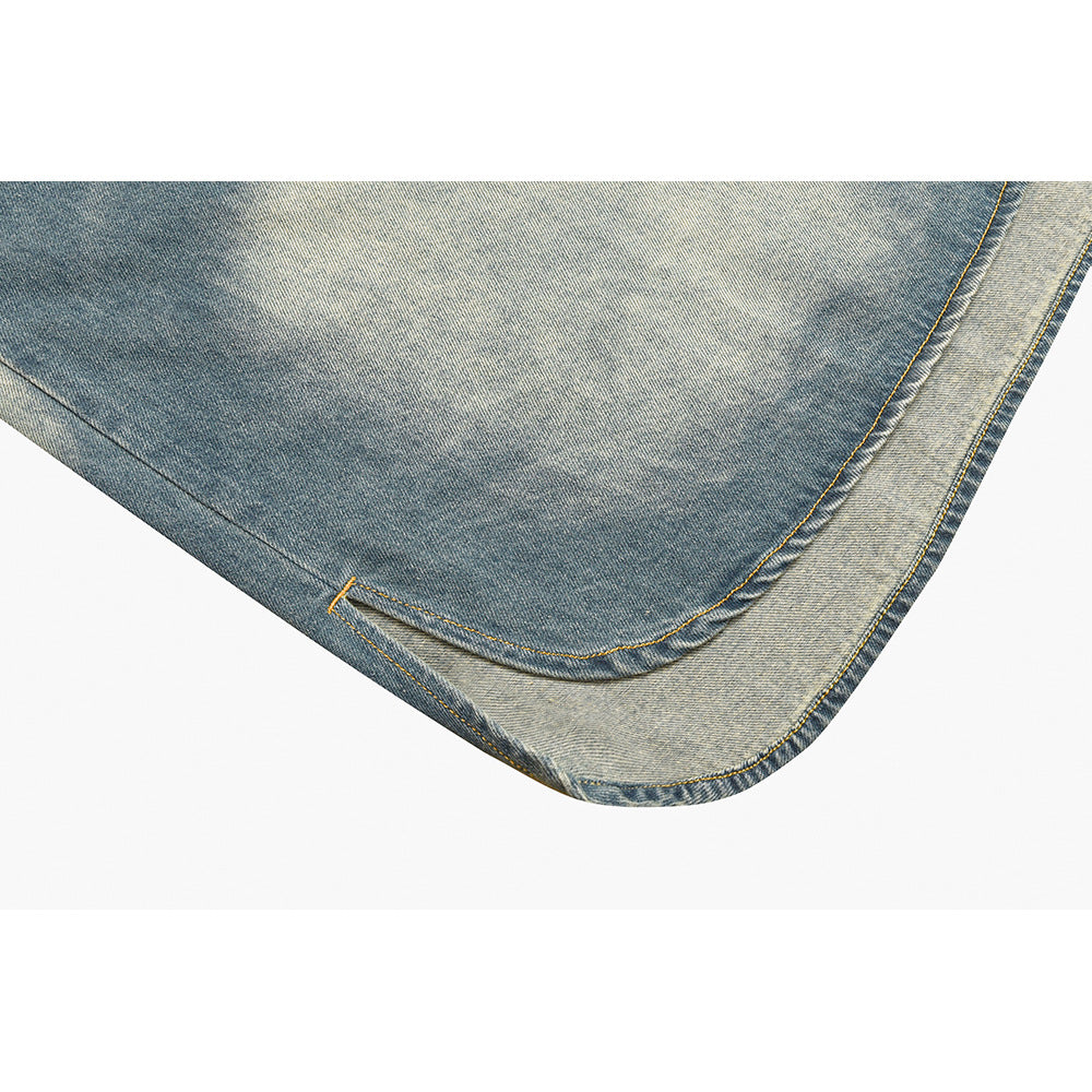 Close-up of the curved hem edge showing layered blue denim, contrasting faded fabric, and yellow stitching.
