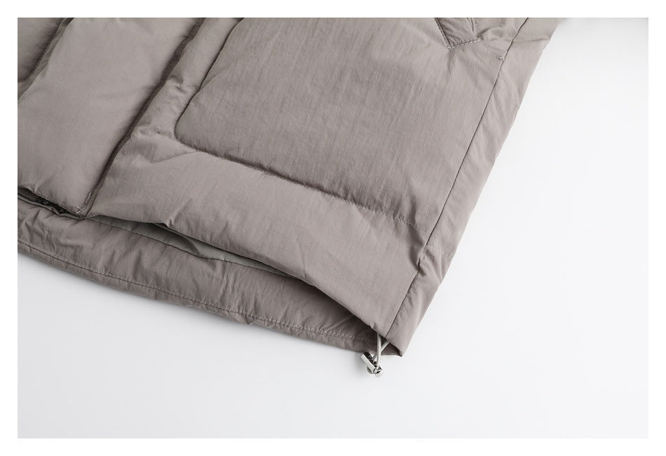 Close-up of the taupe padded jacket hem with a small drawcord toggle.