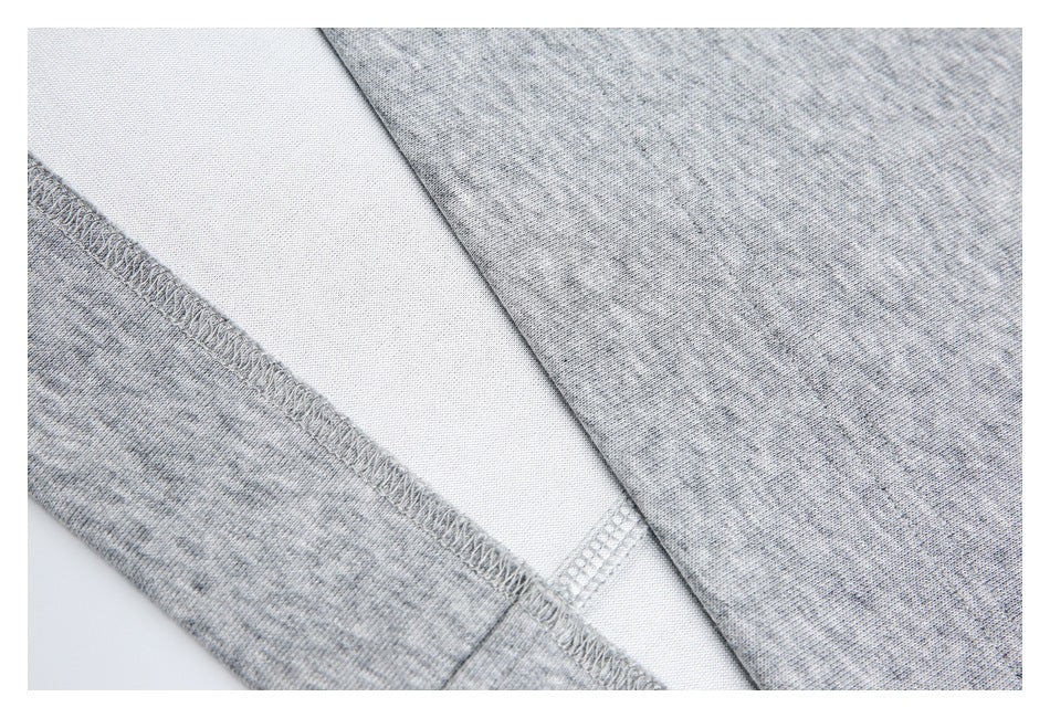 Close-up of light gray knit garment fabric with a stitched seam and white inner panel.
