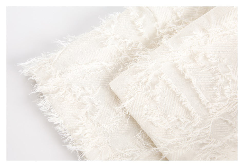 Close-up showing the layered, frayed edges and diagonal weave of ivory fabric.