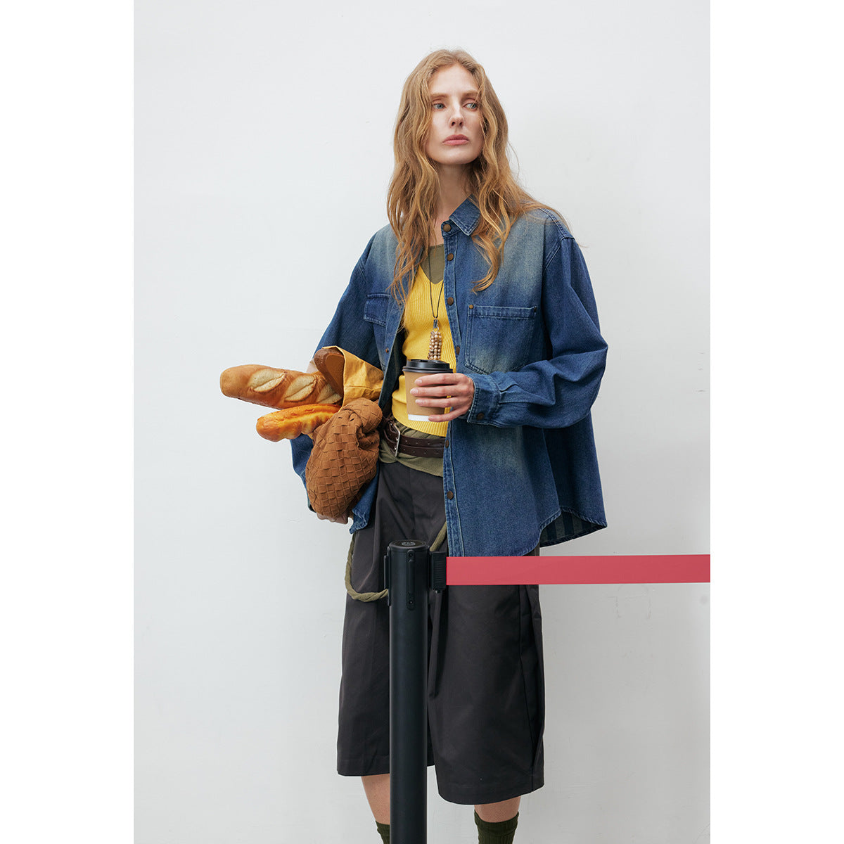 Model wearing an oversized blue denim button-up shirt with two chest pockets, shown with dark shorts.